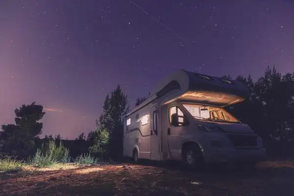 Cena do filme Nomadland, com um trailer parado em um parque nacional à noite.